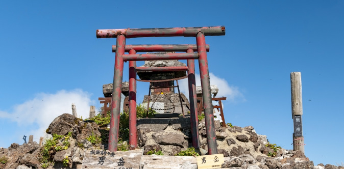 秋田駒ヶ岳の男岳山頂にある神社と青空